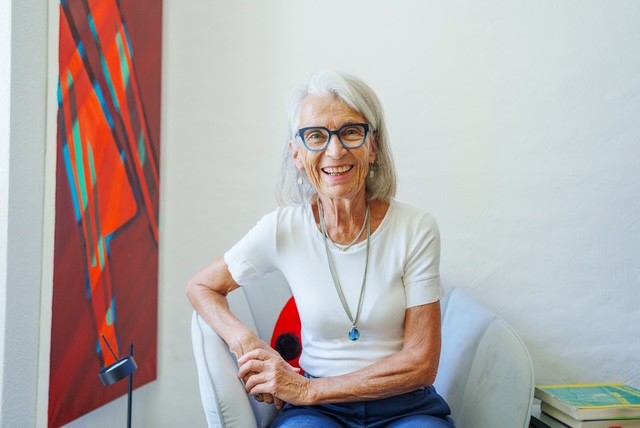 Astro-Sitzung-Silvia Ammann Silvia in ihrer Praxis, neben einem rot leuchtenden Bild, lacht sie in die Kamera